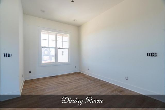 spare room with visible vents, baseboards, and wood finished floors