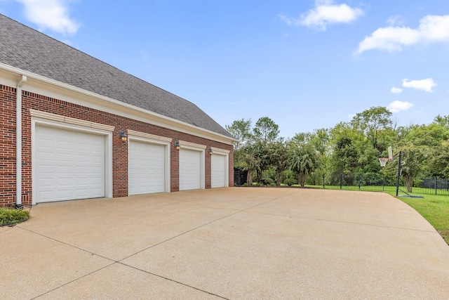 garage featuring driveway and fence