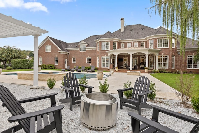 back of house featuring a fire pit, an outdoor pool, a patio, an in ground hot tub, and brick siding