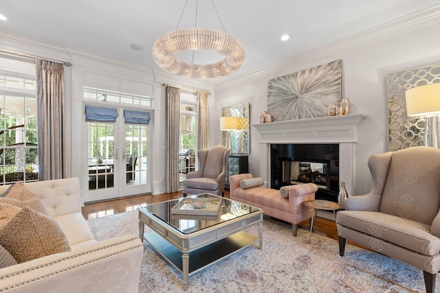 living area featuring recessed lighting, wood finished floors, french doors, ornamental molding, and a glass covered fireplace