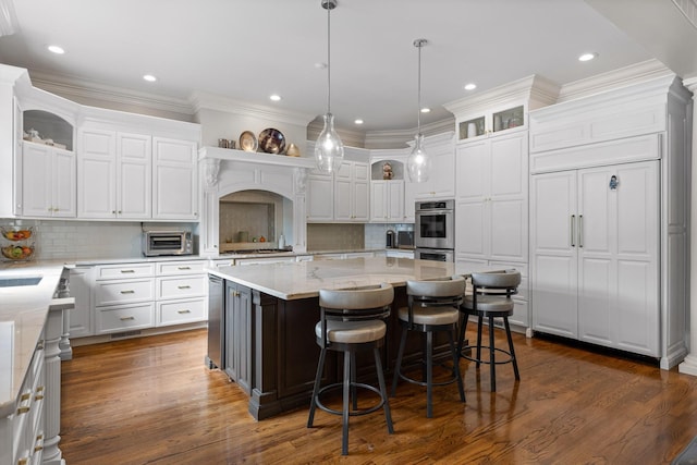 kitchen with stainless steel double oven, a breakfast bar area, white cabinetry, and a center island