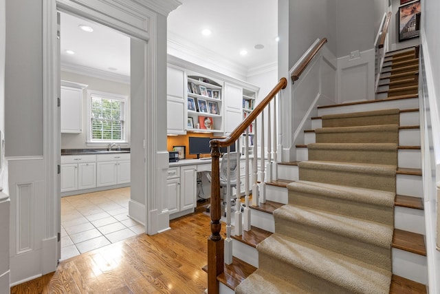 stairway with built in study area, recessed lighting, crown molding, and wood finished floors