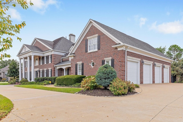 view of front of home featuring a garage, brick siding, driveway, and a chimney