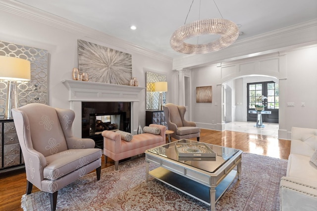 living area featuring arched walkways, ornamental molding, wood finished floors, a multi sided fireplace, and recessed lighting