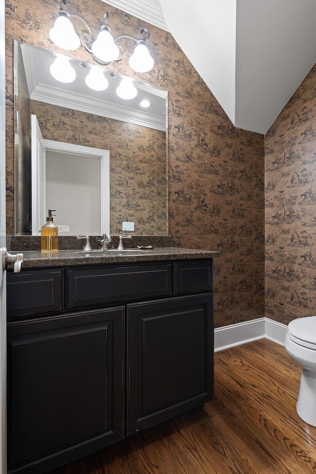 half bath with crown molding, toilet, vanity, baseboards, and wallpapered walls