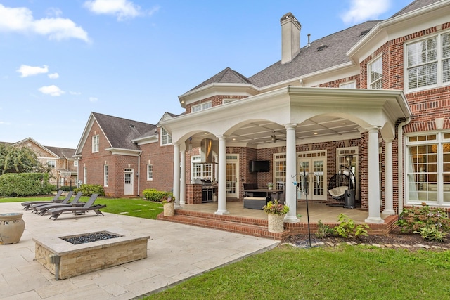 rear view of property with french doors, brick siding, a ceiling fan, an outdoor fire pit, and a patio area