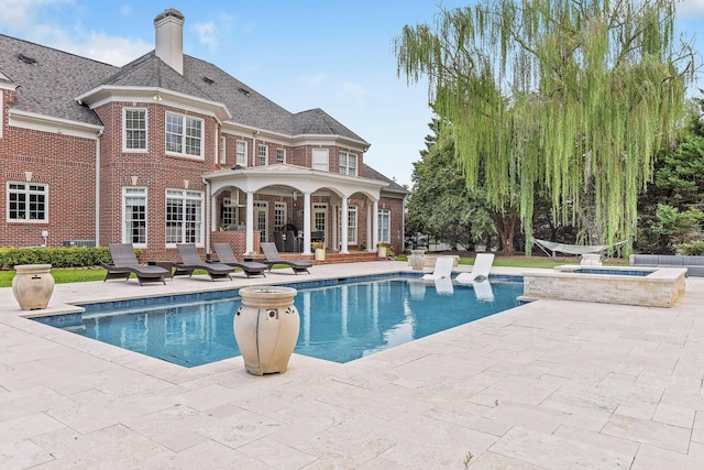 pool featuring an in ground hot tub and a patio area