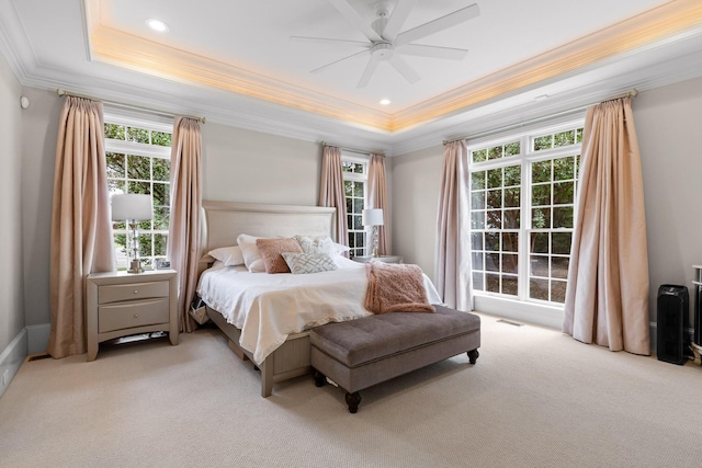 bedroom featuring a ceiling fan, a raised ceiling, crown molding, and light colored carpet