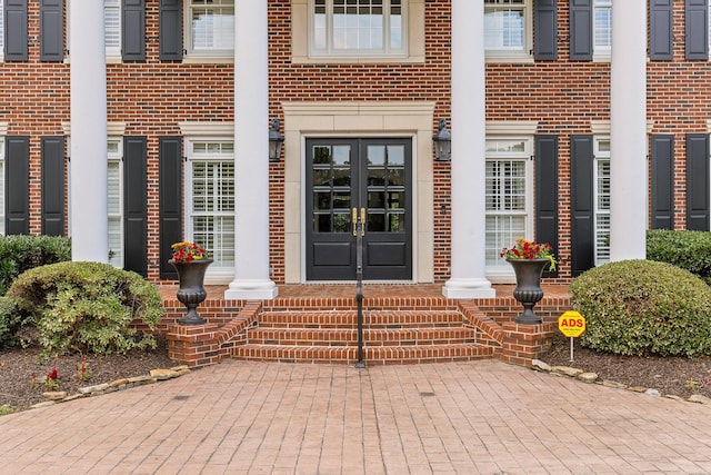 view of exterior entry featuring french doors and brick siding