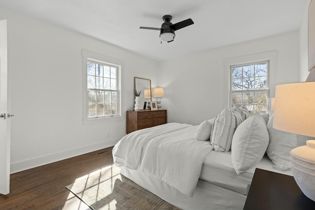 bedroom featuring ceiling fan, wood finished floors, visible vents, and baseboards