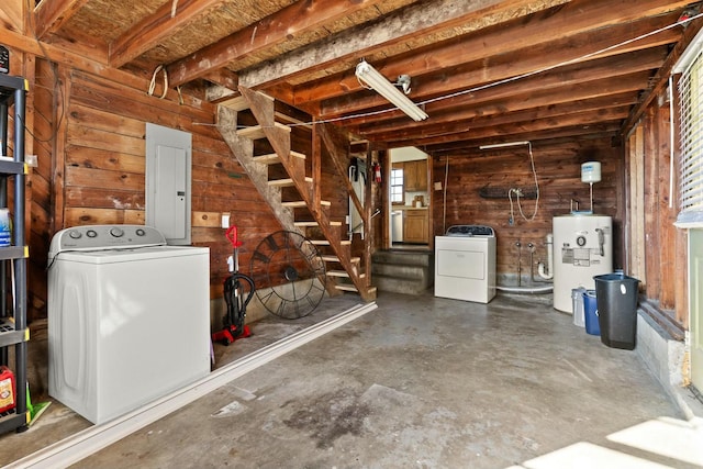 basement with wooden walls, water heater, stairs, electric panel, and washing machine and clothes dryer