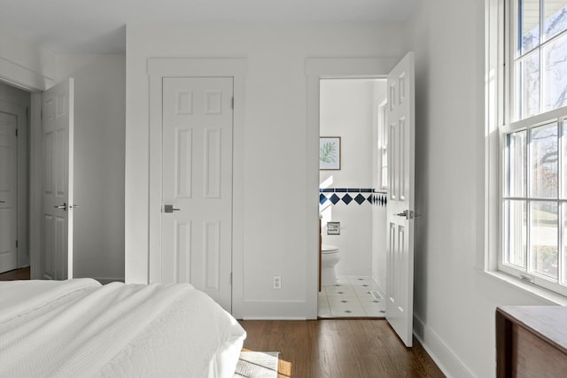 bedroom with tile walls, ensuite bathroom, and wood finished floors