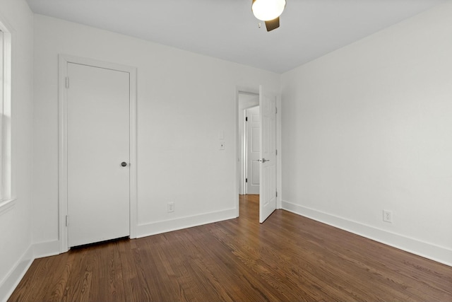 unfurnished bedroom with dark wood-type flooring, ceiling fan, and baseboards