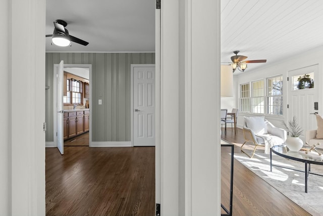 corridor featuring a sink, ornamental molding, dark wood finished floors, and baseboards