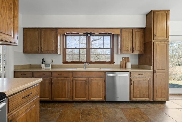 kitchen featuring dishwasher, light countertops, a sink, and brown cabinets