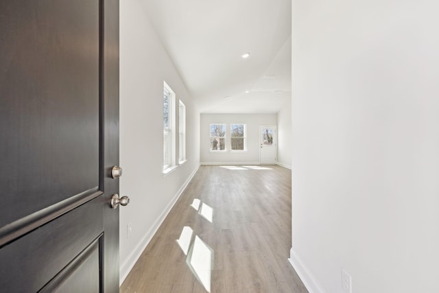 entrance foyer featuring light wood-type flooring, baseboards, and lofted ceiling