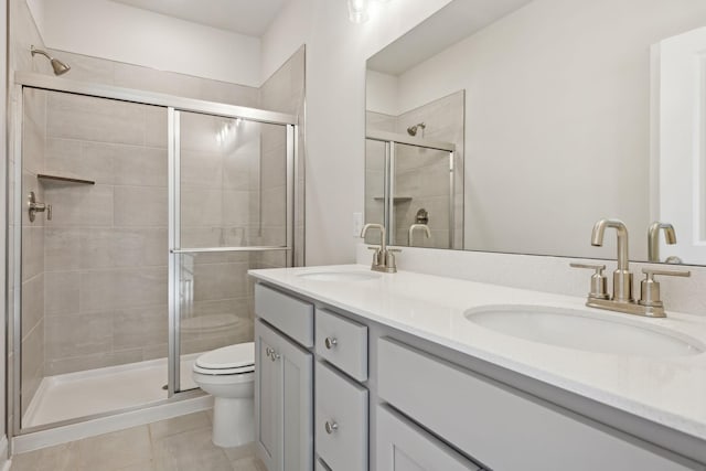 full bath with a sink, a shower stall, toilet, and double vanity