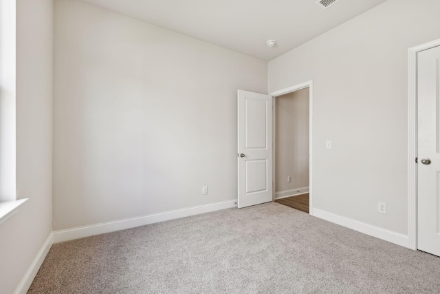 unfurnished room featuring carpet flooring, visible vents, and baseboards