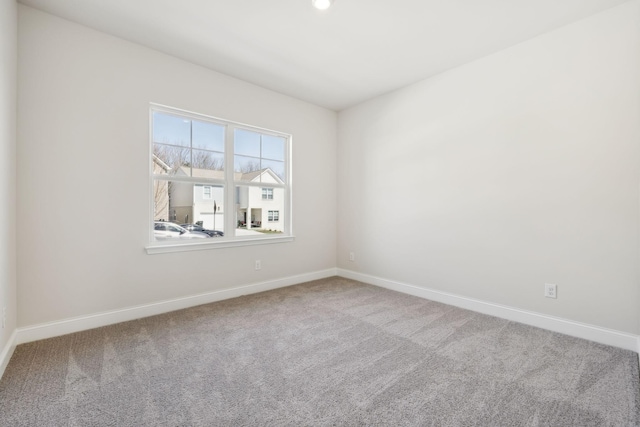 carpeted spare room featuring baseboards