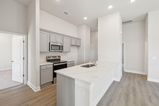 kitchen with visible vents, stainless steel appliances, a sink, and gray cabinetry