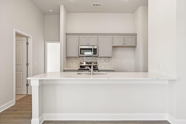 kitchen with visible vents, decorative backsplash, appliances with stainless steel finishes, gray cabinets, and a sink