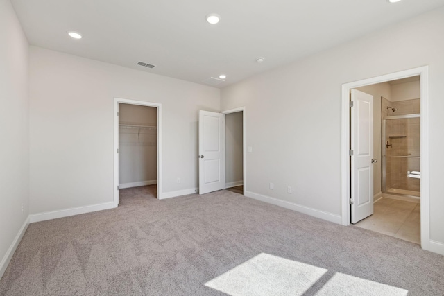 unfurnished bedroom with visible vents, a walk in closet, carpet flooring, and recessed lighting