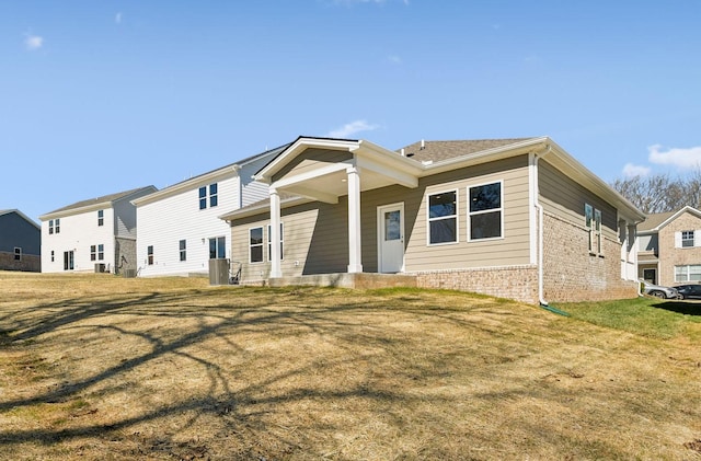 view of front of home with brick siding, a front yard, and cooling unit