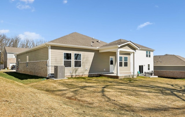 rear view of house featuring a patio area, central AC, a yard, and roof with shingles