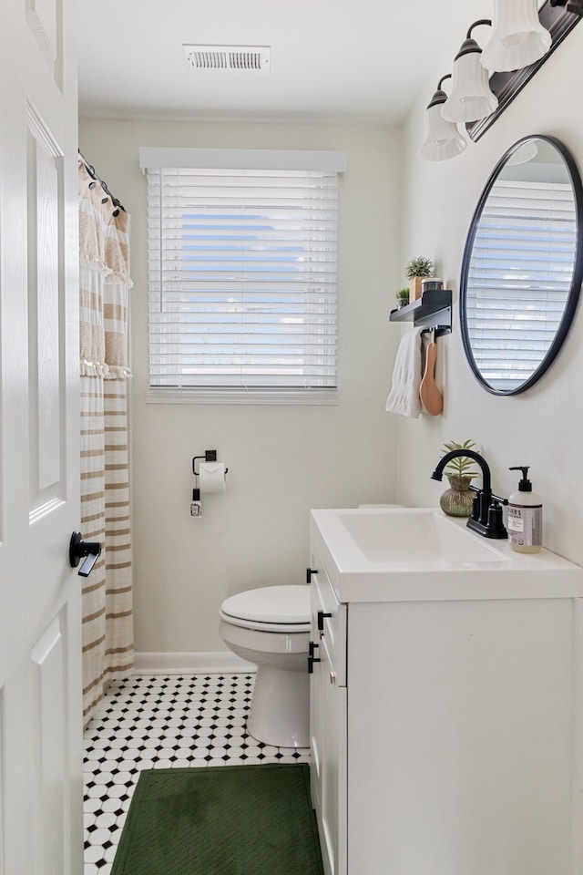 bathroom with curtained shower, toilet, vanity, visible vents, and baseboards