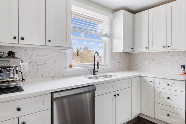 kitchen with backsplash, light countertops, stainless steel dishwasher, white cabinetry, and a sink