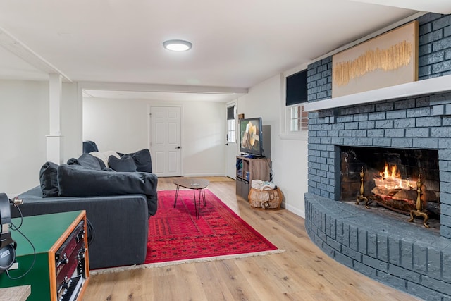 living area with a fireplace, baseboards, and wood finished floors