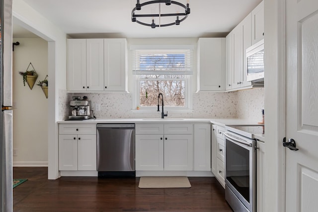 kitchen featuring dark wood-style floors, stainless steel appliances, light countertops, white cabinets, and a sink