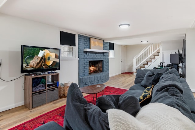 living room featuring baseboards, a fireplace, stairway, and wood finished floors