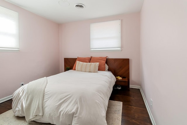 bedroom with wood finished floors, visible vents, and baseboards