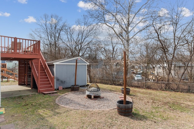 view of yard with an outbuilding, a deck, fence, stairs, and a shed