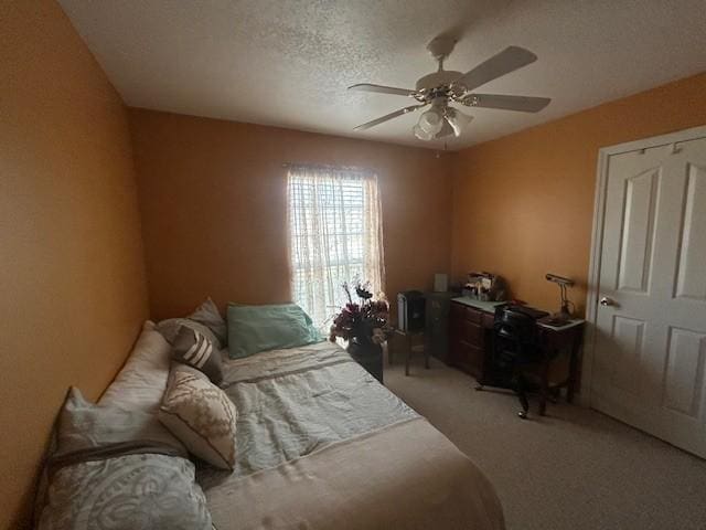 bedroom with ceiling fan, a textured ceiling, and light colored carpet