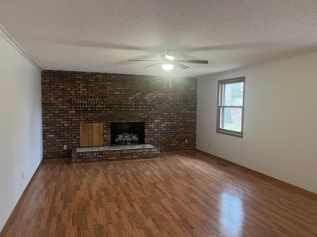 unfurnished living room featuring a textured ceiling, crown molding, a fireplace, and wood finished floors