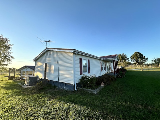 view of side of property with a lawn and cooling unit