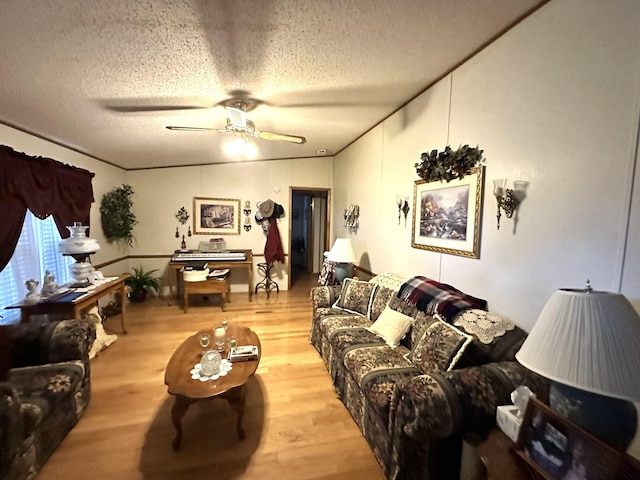 living room with a textured ceiling, ceiling fan, and light wood-style flooring