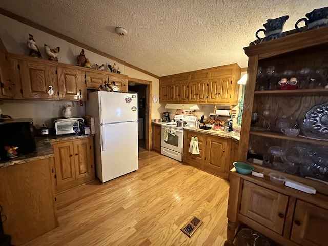 kitchen featuring brown cabinets, visible vents, light wood-style floors, vaulted ceiling, and white appliances