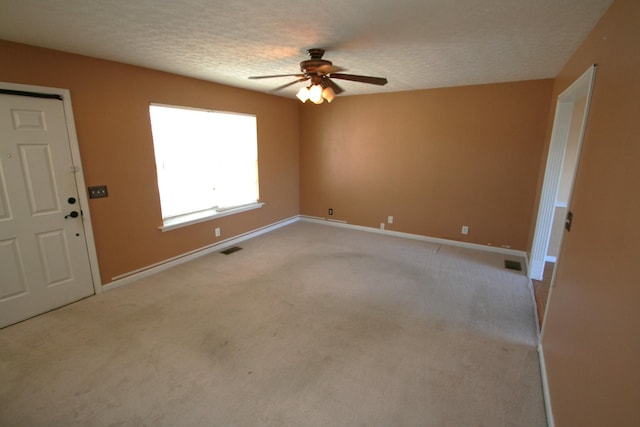 spare room with a textured ceiling, light carpet, and visible vents