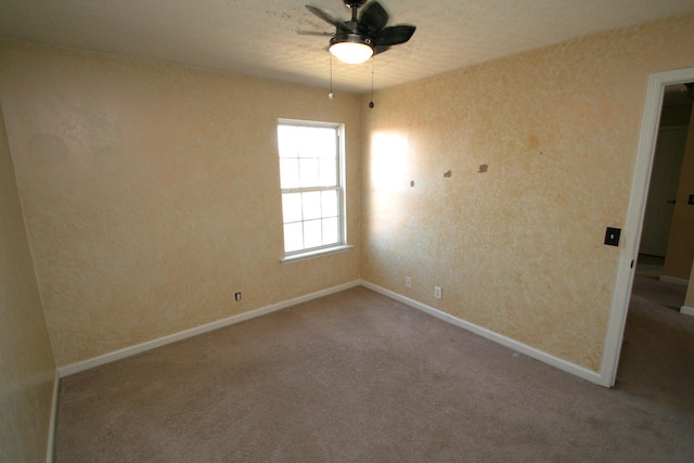 carpeted empty room with ceiling fan and baseboards