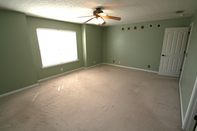 unfurnished room with a textured ceiling, visible vents, baseboards, a ceiling fan, and carpet