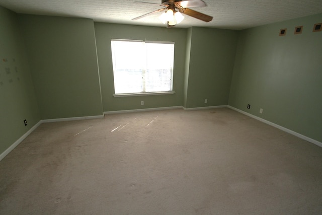 spare room with light carpet, ceiling fan, a textured ceiling, and baseboards