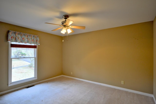 empty room featuring visible vents, ceiling fan, light carpet, and baseboards