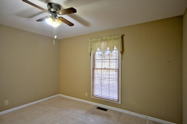 spare room featuring a ceiling fan, light colored carpet, visible vents, and baseboards