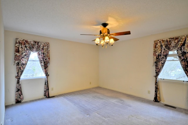 unfurnished room with a textured ceiling, ceiling fan, visible vents, and baseboards