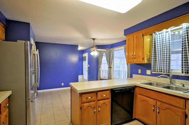 kitchen featuring freestanding refrigerator, light tile patterned flooring, a sink, dishwasher, and a peninsula