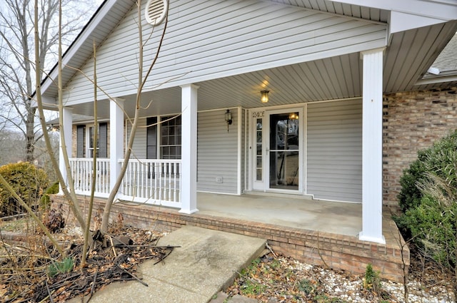 property entrance featuring covered porch and brick siding