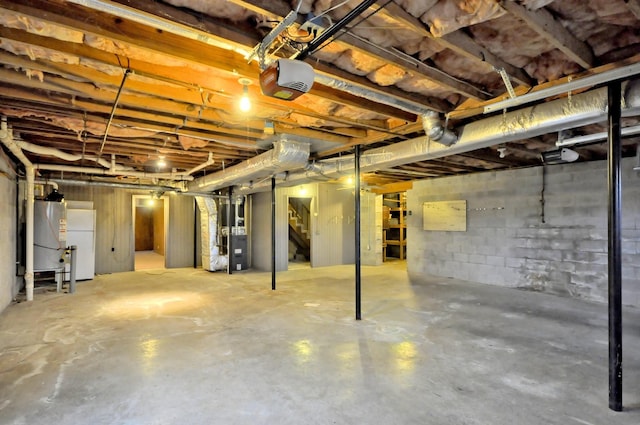 unfinished below grade area featuring heating unit, water heater, and freestanding refrigerator